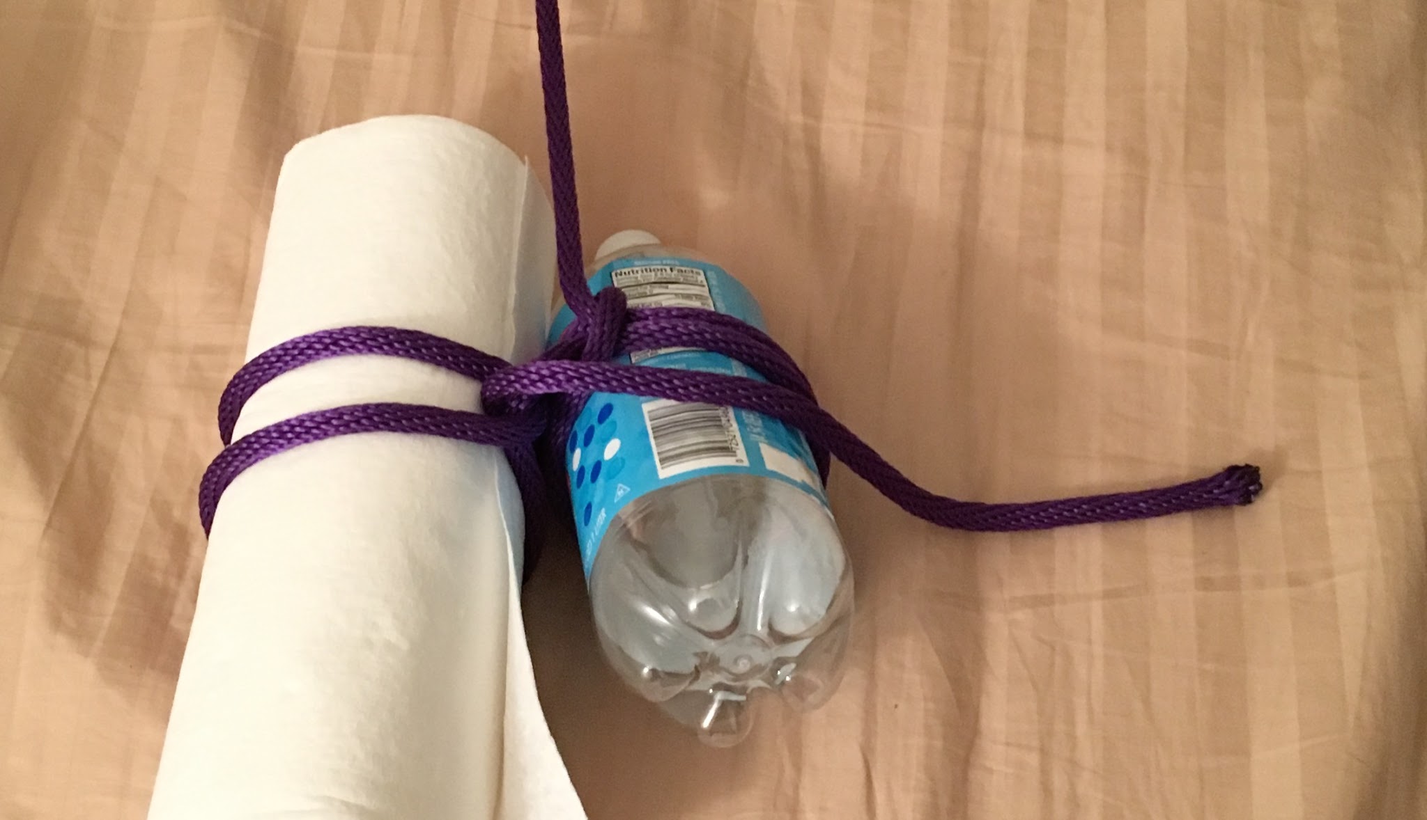 rope tied around a paper towel roll and empty seltzer bottle